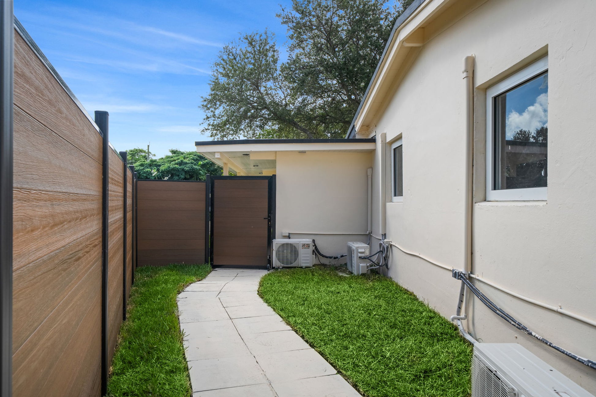 Side yard walkway with wood-grain composite privacy fence and matching composite gate beside residential home