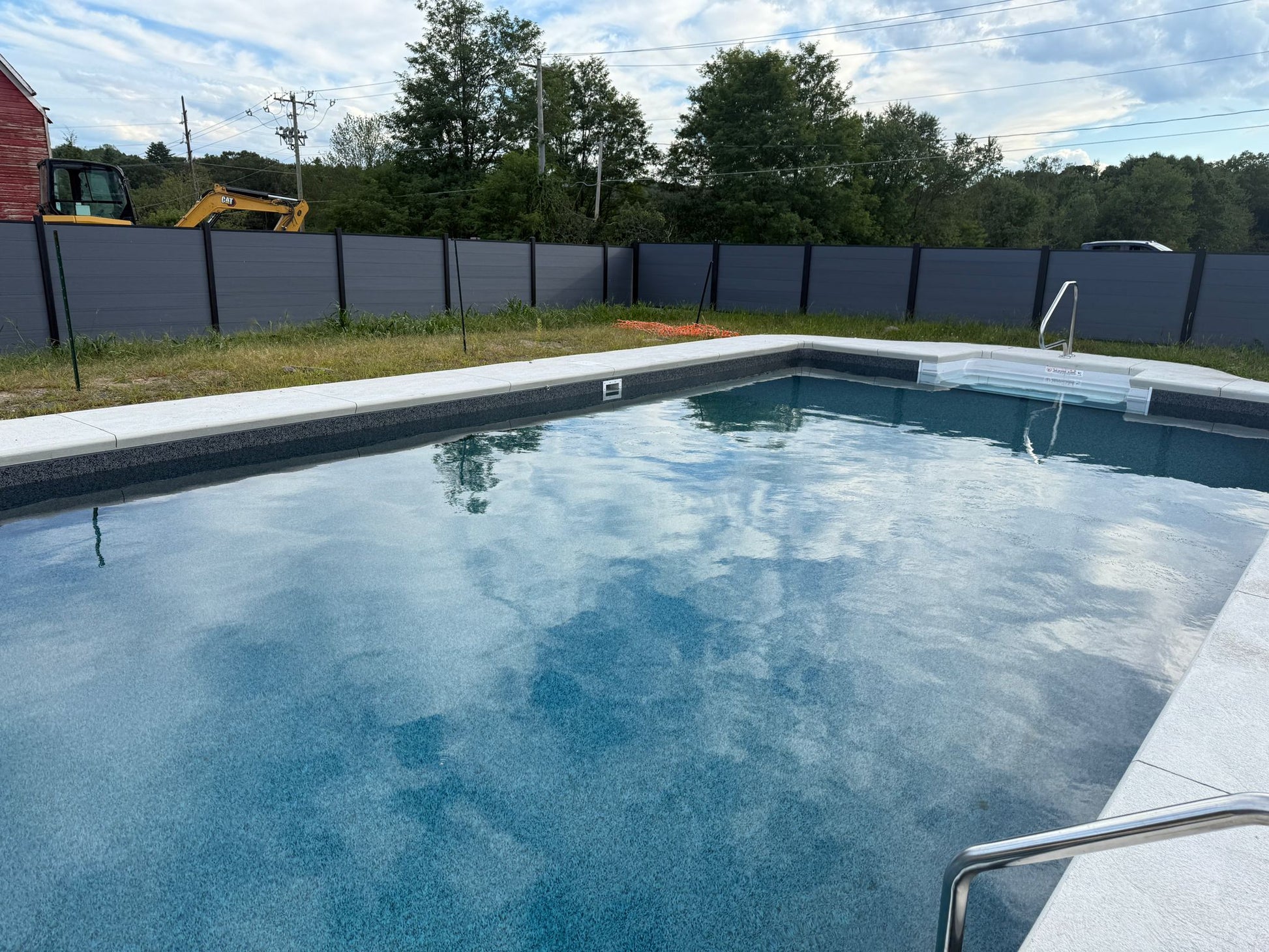 Backyard swimming pool enclosed with gray composite privacy fence panels for modern outdoor design